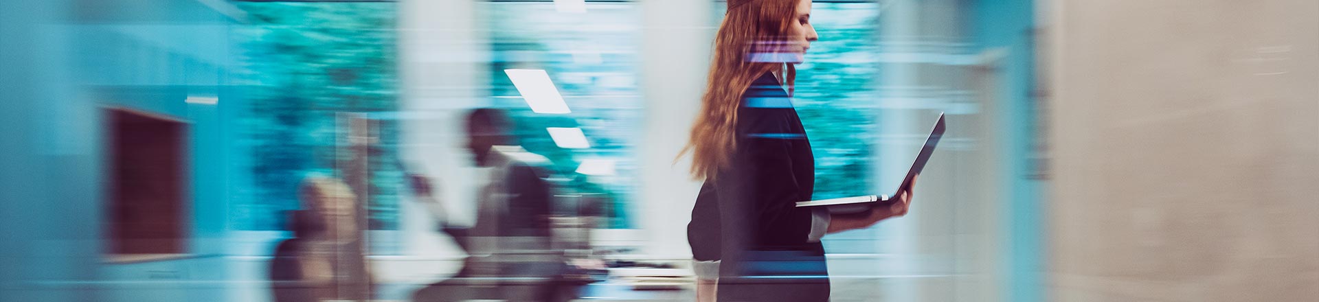 Blurry office scene with woman walking past meeting room