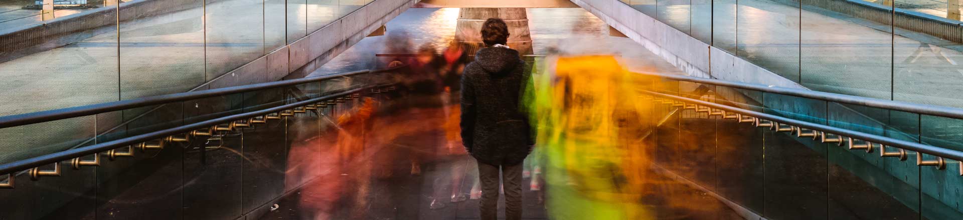 Man on stairs with many fast moving images of people around him