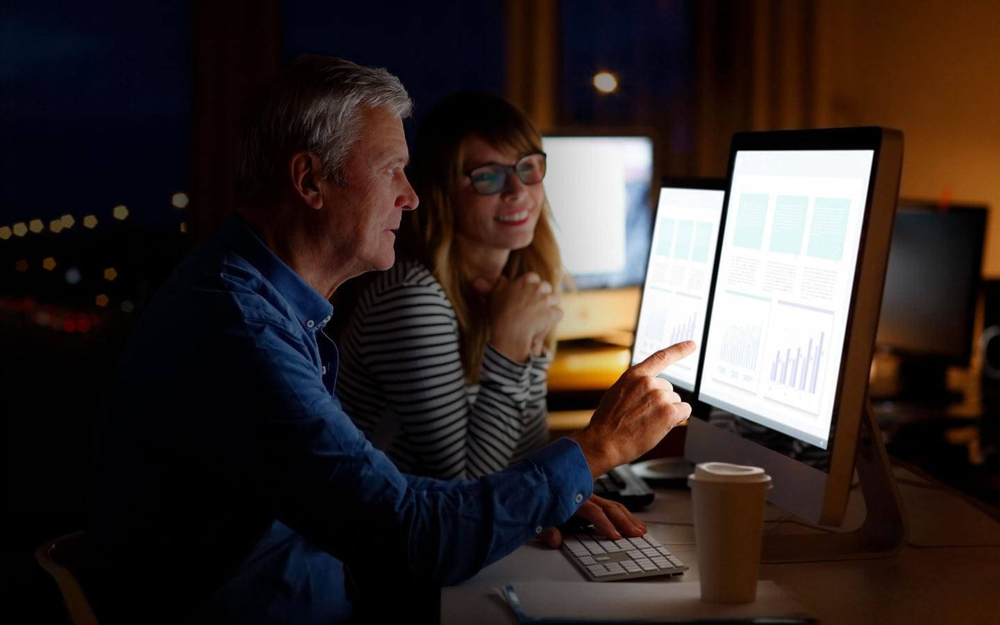A man and a woman looking at monitor screens with data