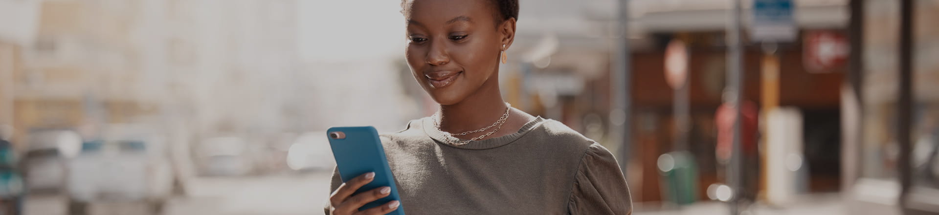 A woman smiling at a cellphone screen