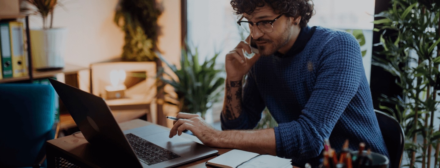 Man working on a laptop and talking on a mobile phone