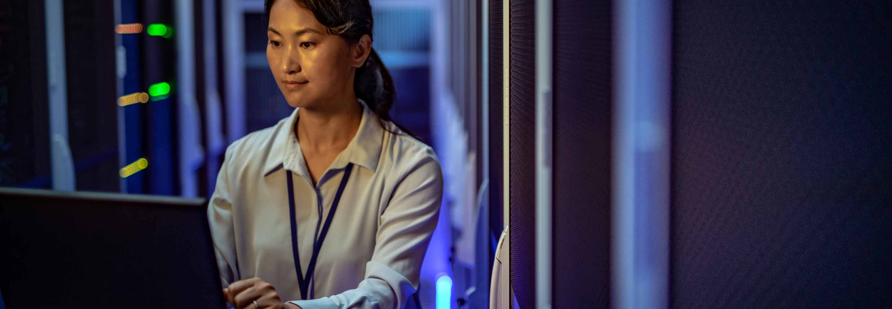 Woman in a server room sitting at a laptop