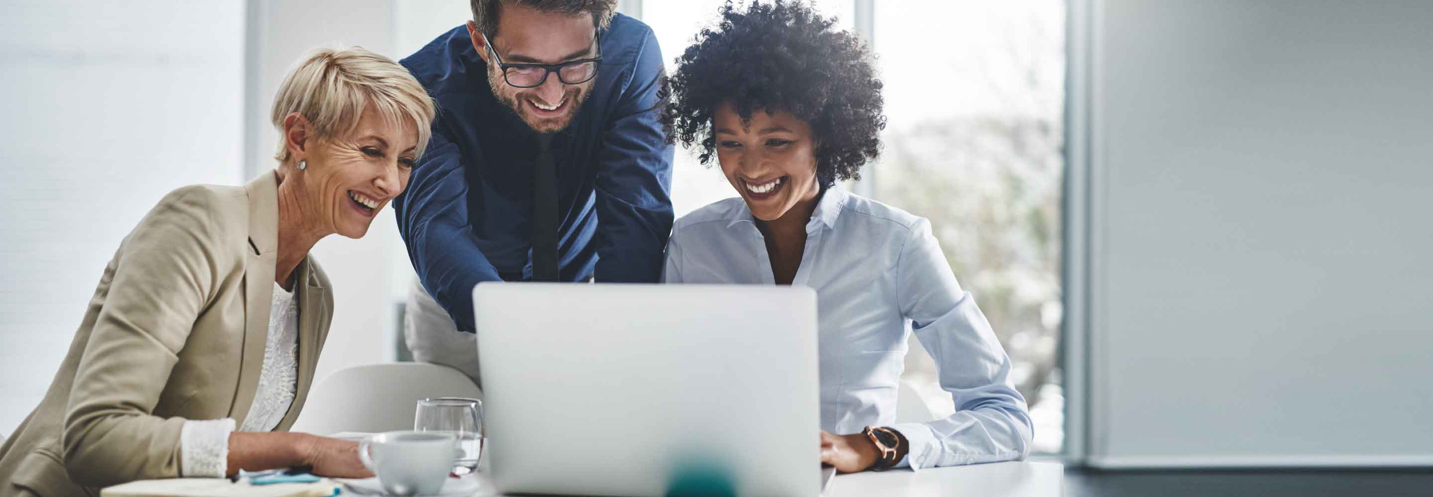 Three colleagues smiling at a computer screen
