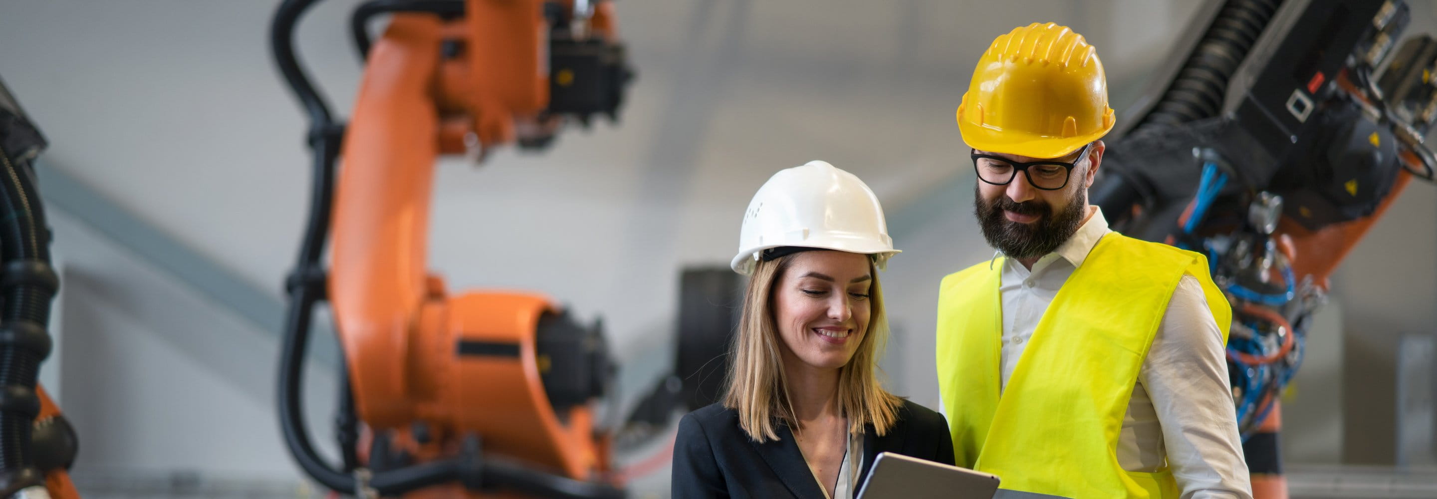 A man and a woman wearing helmets and looking at a tablet screen