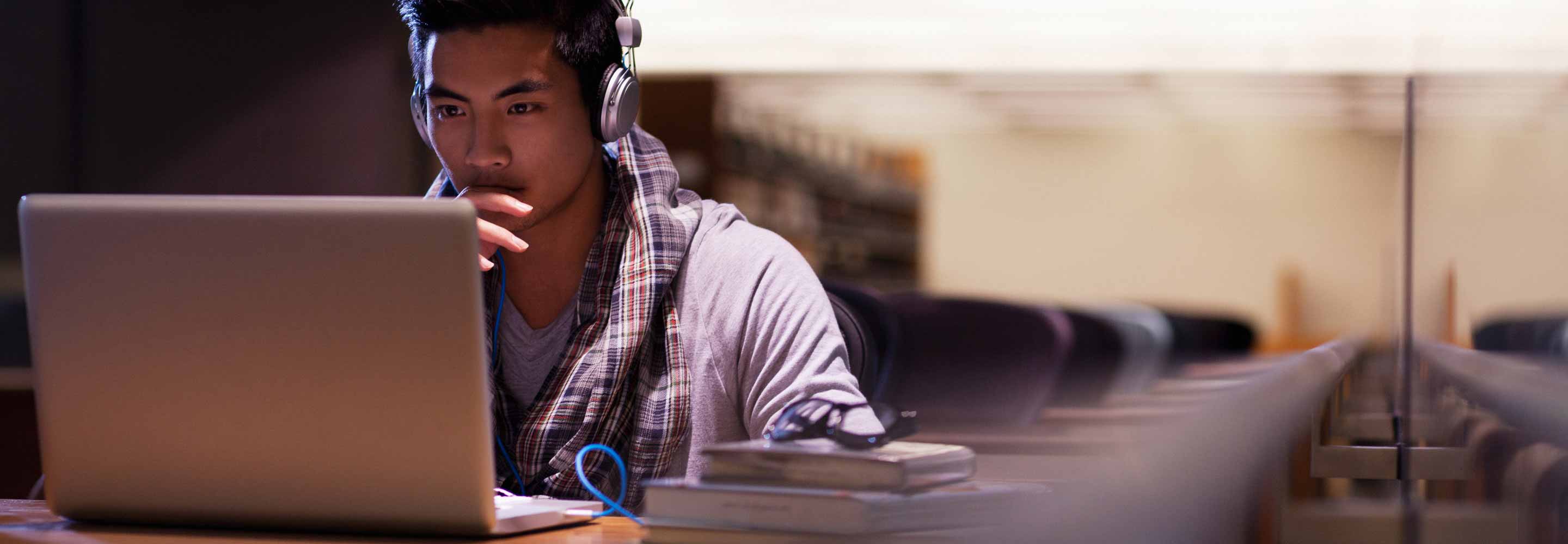 A man with headphones looking at a laptop screen