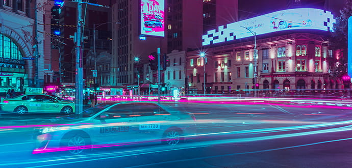 Cars on a road with blue and pink light trails at night 